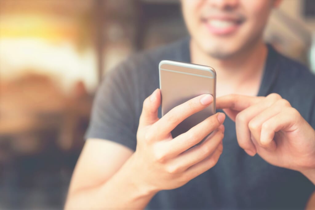 Happy man using smartphone at modern coffee shop, he chatting Online Messaging on mobile phone. copy space